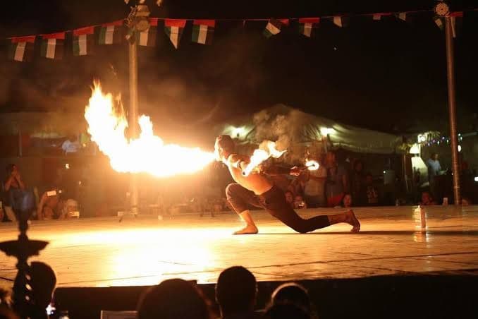 Fire performer on the stage of the desert camp at night