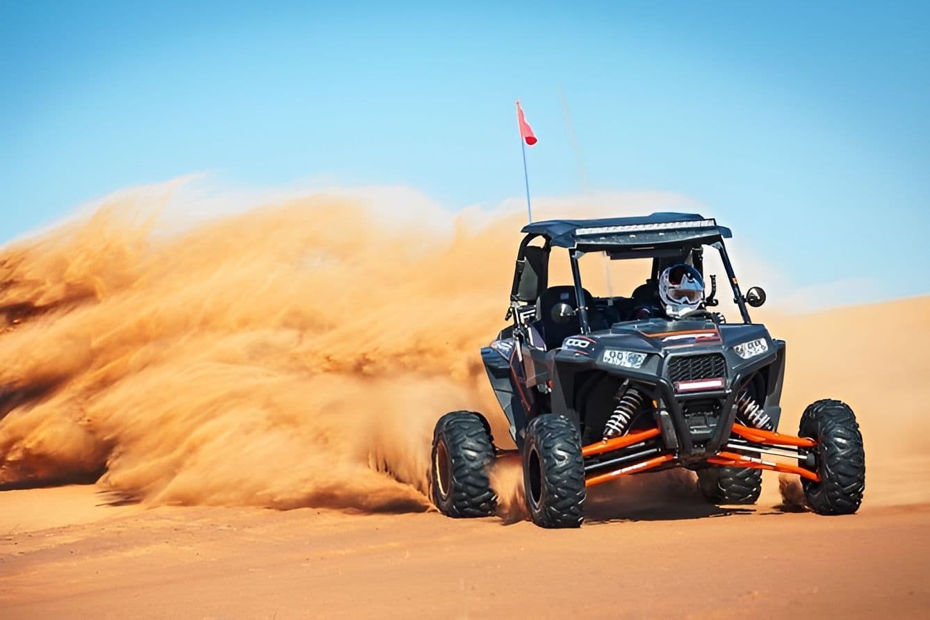 Dune buggy driving through the sand under a blue sky