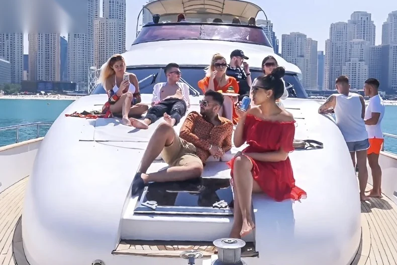 Guests relaxing on the front deck of a shared luxury yacht with the Dubai Marina skyline