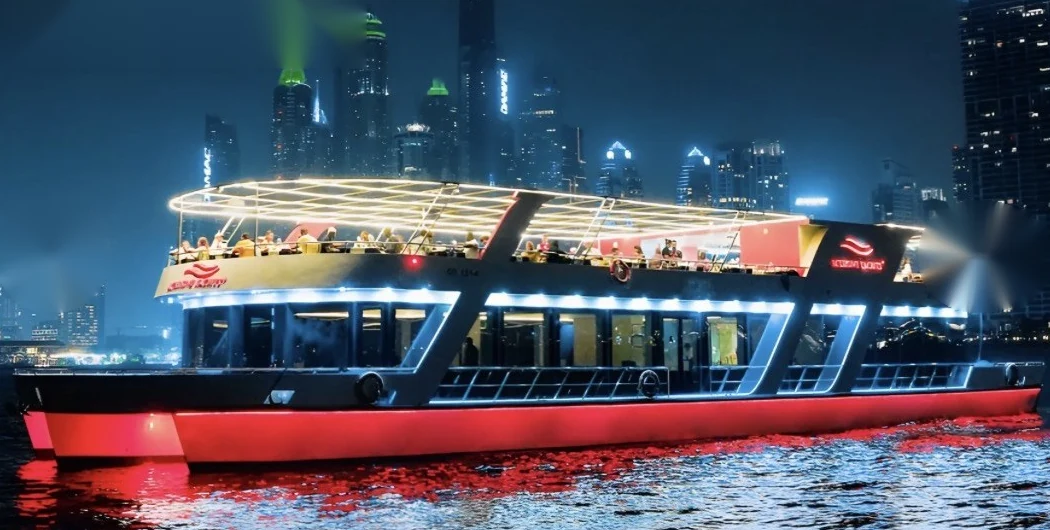 Illuminated dinner cruise boat at night with the Dubai Marina skyline